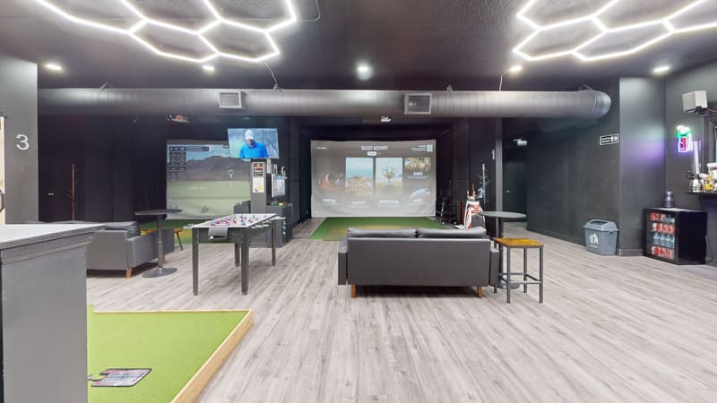 Club X Indoor Golf — wide lounge view with simulator bay, bar, putting area, and seating, set for private events
